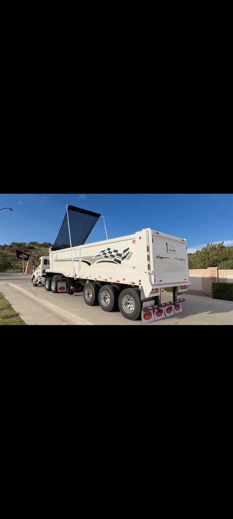 White commercial dump truck with open black hydraulic lift bed